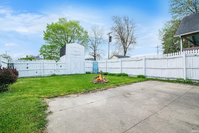 view of yard featuring an outdoor structure, a fire pit, a fenced backyard, and a patio area