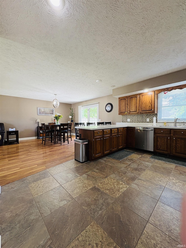 3701 Wethersfield Dr, Evansville, IN 47725 - kitchen with stainless steel dishwasher, light countertops, a peninsula, a sink, and a textured ceiling