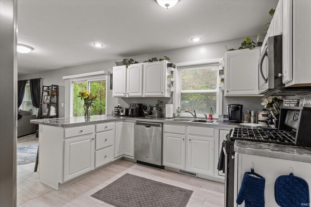 29930 Prairieview Farms Blvd, Elkhart, IN 46514 - kitchen featuring a peninsula, light wood-type flooring, white cabinets, a sink, and stainless steel appliances