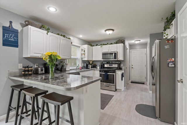 29930 Prairieview Farms Blvd, Elkhart, IN 46514 - kitchen featuring a peninsula, white cabinets, a kitchen breakfast bar, and stainless steel appliances