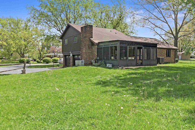 4231 N Conner Dr, Marion, IN 46952 - rear view of house with a garage, driveway, a sunroom, central air condition unit, and a yard