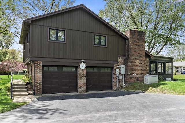4231 N Conner Dr, Marion, IN 46952 - exterior space featuring an attached garage, aphalt driveway, a chimney, and brick siding