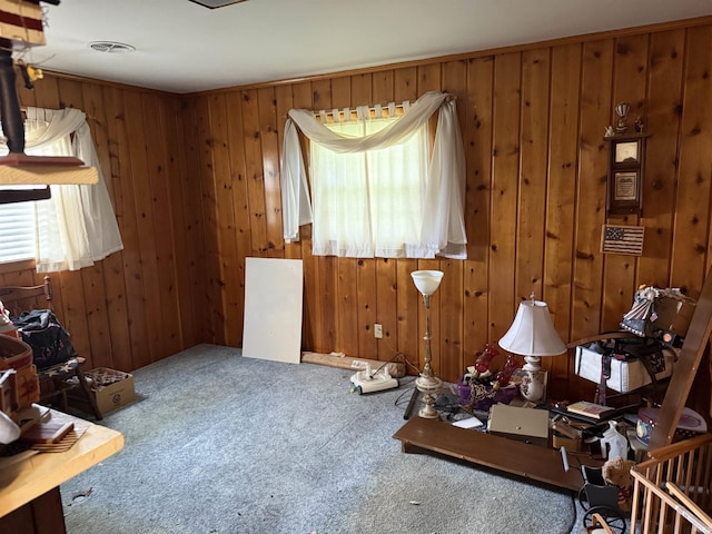 miscellaneous room with a healthy amount of sunlight, carpet flooring, wood walls, and visible vents