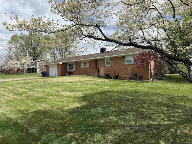 back of property featuring an attached garage, brick siding, a yard, and a chimney