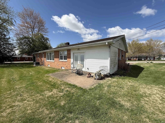 rear view of property featuring a yard, a chimney, cooling unit, and brick siding
