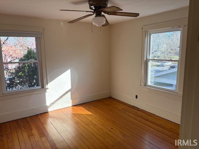 spare room featuring plenty of natural light, light wood finished floors, and baseboards