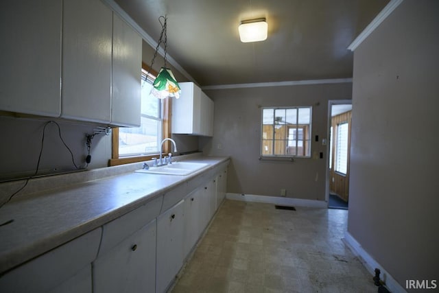 kitchen with crown molding, a sink, white cabinetry, baseboards, and light floors