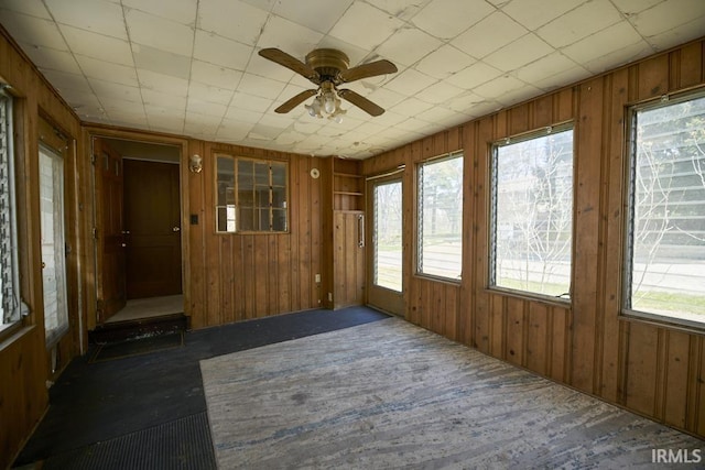 unfurnished sunroom with carpet flooring and wood walls