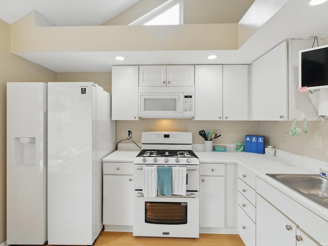 kitchen featuring light countertops, white cabinets, white appliances, and a sink