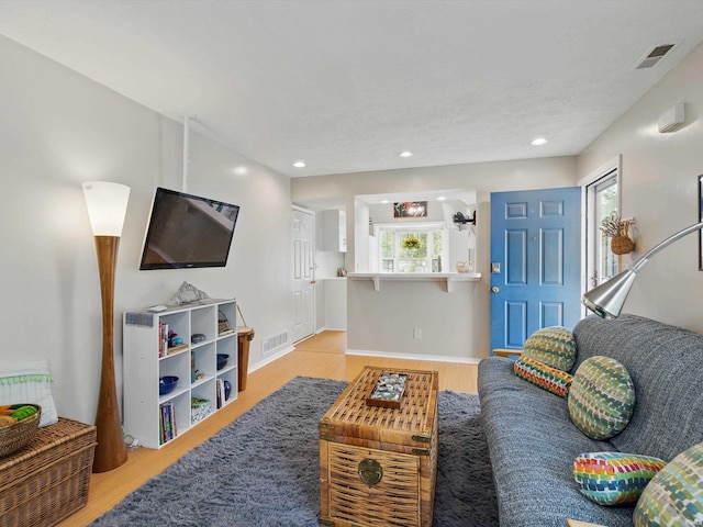 living area with light wood-style floors, baseboards, recessed lighting, and visible vents