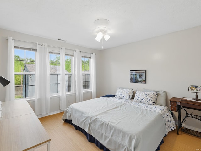 bedroom with visible vents, multiple windows, and light wood-style floors