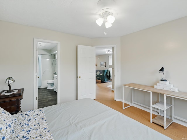 bedroom featuring baseboards, wood finished floors, and ensuite bath