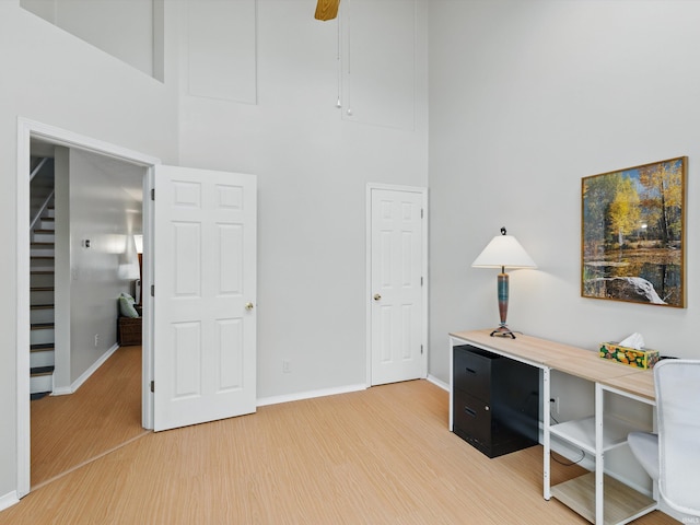 office with baseboards, a high ceiling, and light wood-style flooring