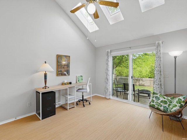 home office with baseboards, a skylight, light wood finished floors, and high vaulted ceiling