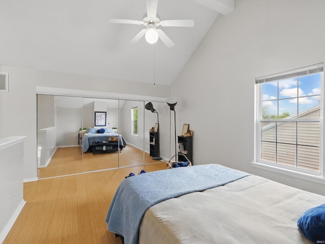 bedroom with visible vents, a closet, wood finished floors, baseboards, and high vaulted ceiling