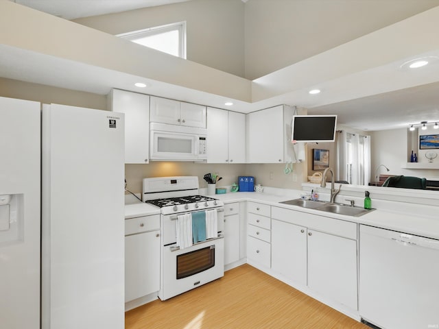 kitchen featuring white cabinets, a sink, light wood finished floors, white appliances, and light countertops