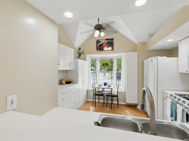 kitchen with white cabinets, ceiling fan, a sink, stainless steel range with electric stovetop, and light wood-style flooring
