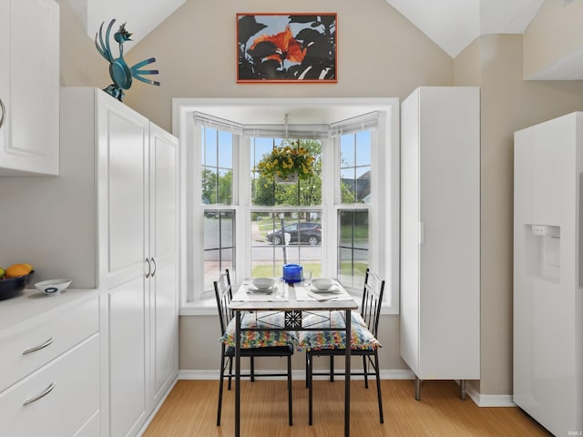 dining area featuring baseboards, vaulted ceiling, and light wood-type flooring