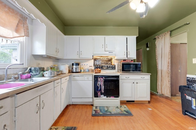 kitchen featuring white cabinets, a sink, white appliances, light countertops, and under cabinet range hood