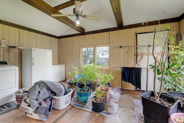 interior space featuring a ceiling fan, wood walls, washer / dryer, and lofted ceiling with beams