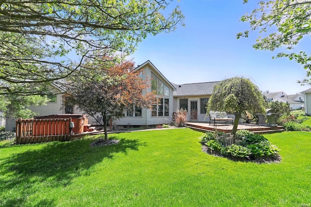 back of house with a lawn, a wooden deck, and a hot tub