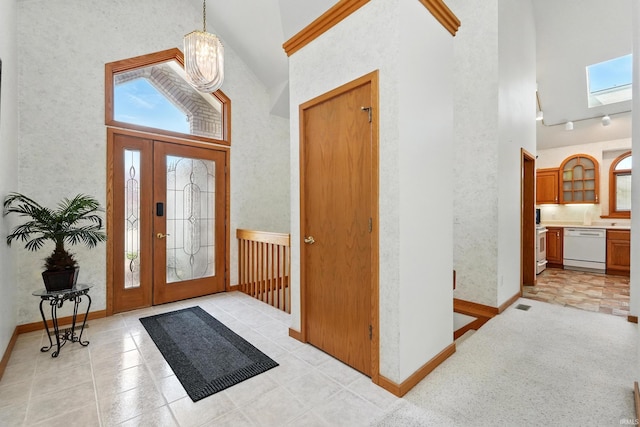 entrance foyer featuring baseboards, high vaulted ceiling, a chandelier, and a skylight