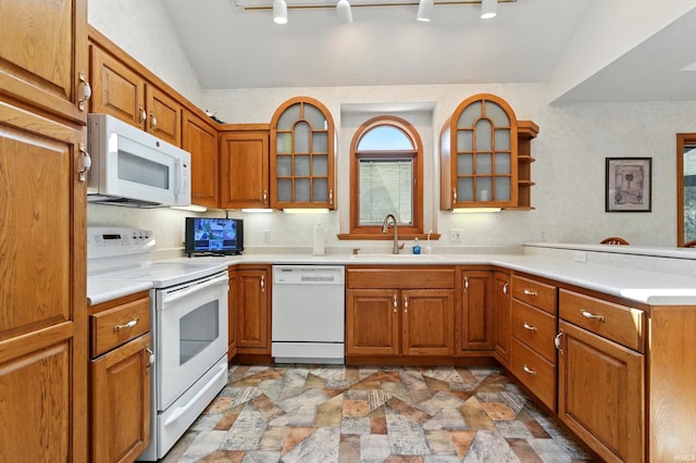 kitchen featuring a sink, brown cabinets, a peninsula, and white appliances
