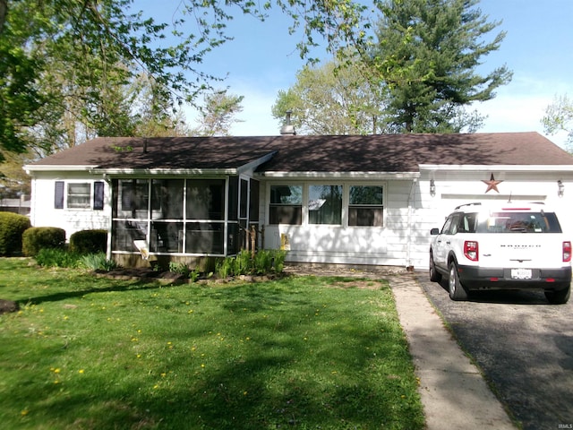 ranch-style home with a sunroom, a garage, a front lawn, and aphalt driveway
