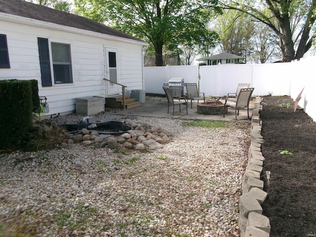 view of yard featuring a fenced backyard, entry steps, a patio area, central air condition unit, and a fire pit