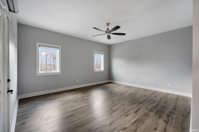 unfurnished room featuring baseboards, a ceiling fan, and dark wood finished floors