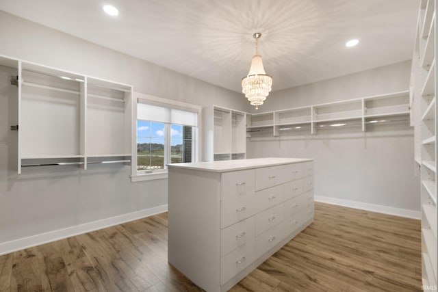 walk in closet with a chandelier and wood finished floors