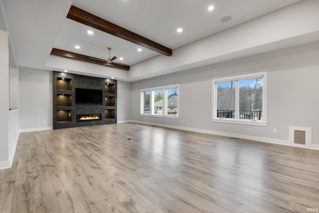 unfurnished living room featuring wood finished floors, beam ceiling, a fireplace, baseboards, and recessed lighting
