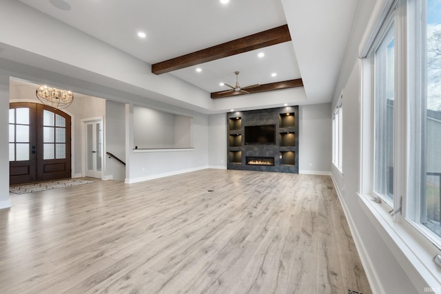 unfurnished living room featuring a healthy amount of sunlight, french doors, and light wood-type flooring