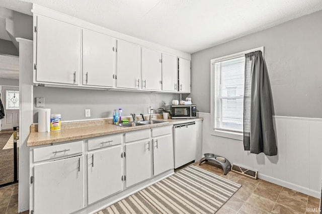 kitchen featuring visible vents, white dishwasher, light countertops, stainless steel microwave, and a sink