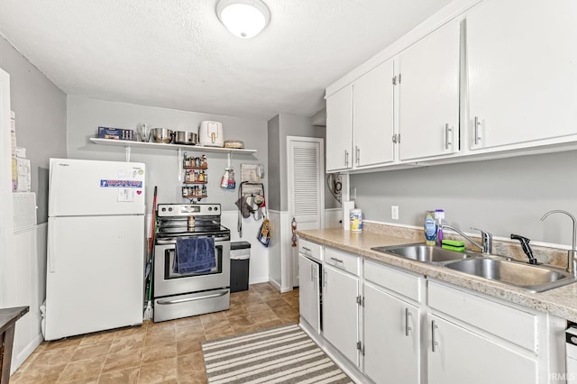 kitchen featuring freestanding refrigerator, electric range, light countertops, white cabinets, and a sink
