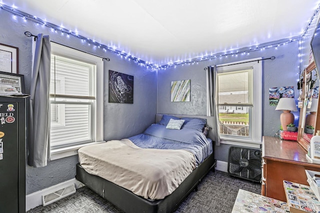 bedroom featuring baseboards, a textured wall, and visible vents
