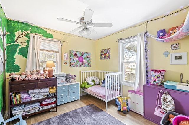 bedroom featuring ceiling fan, multiple windows, and wood finished floors