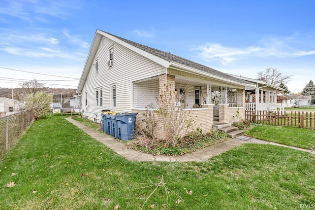 view of side of property featuring covered porch, a lawn, and a fenced backyard
