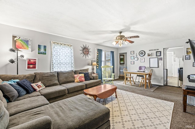 carpeted living room with baseboards and a ceiling fan