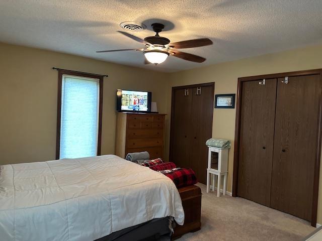 8615 Timbermill Pl, Fort Wayne, IN 46804 - bedroom with two closets, light colored carpet, ceiling fan, and a textured ceiling