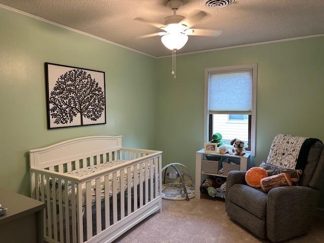 8615 Timbermill Pl, Fort Wayne, IN 46804 - carpeted bedroom with crown molding, a nursery area, a textured ceiling, and a ceiling fan