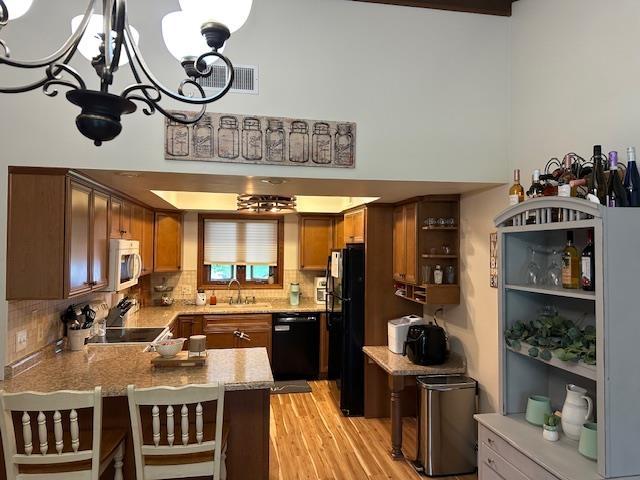 8615 Timbermill Pl, Fort Wayne, IN 46804 - kitchen featuring black appliances, a peninsula, a chandelier, backsplash, and a sink