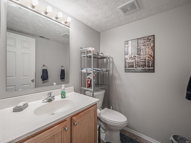 half bath with toilet, a textured ceiling, visible vents, and vanity