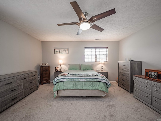 bedroom featuring ceiling fan, light carpet, a textured ceiling, and visible vents