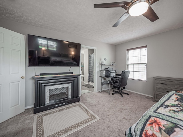 carpeted bedroom with a ceiling fan, a textured ceiling, baseboards, and ensuite bath