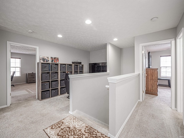 corridor featuring carpet, a healthy amount of sunlight, and an upstairs landing