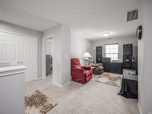 carpeted living room featuring visible vents, a textured ceiling, and baseboards