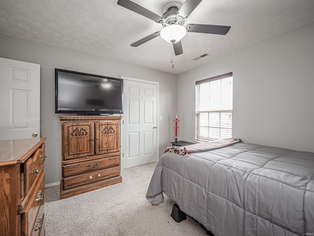 bedroom with ceiling fan, light colored carpet, a textured ceiling, and visible vents