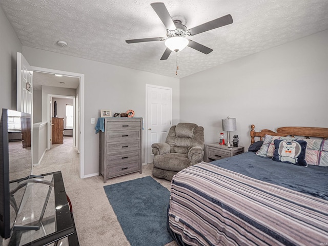 bedroom with light colored carpet, a textured ceiling, ceiling fan, and baseboards