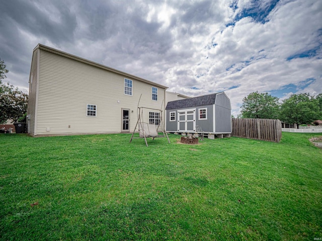 rear view of property with an outdoor structure, a shed, a yard, and fence